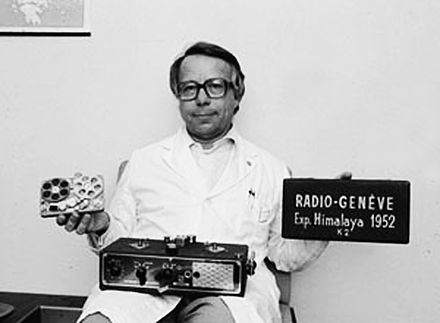 Stefan Kudelski holding a radio and a sign with 'Radio-Genève' written on it © Erling Mandelmann, CC BY-SA