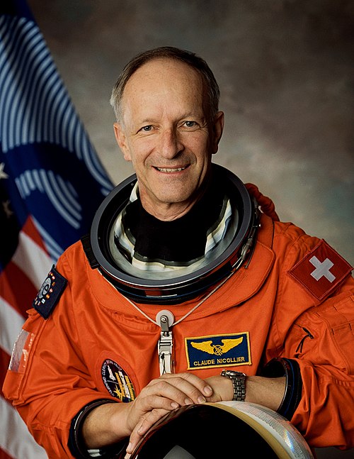 Claude Nicollier wearing his astronaut suit and holding his astronaut helmet. © NASA-ESA, CC BY-SA