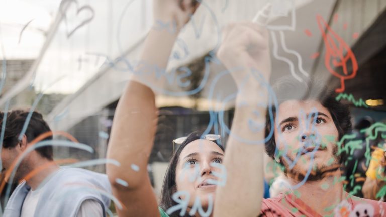 Deux personnes dessinant sur un mur transparent