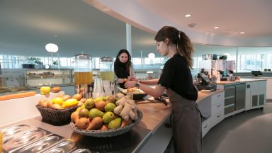 Une employée sert une cliente, avec des fruits frais et du jus sur le comptoir du Takinoa, l'ancienne cafetariat de la bibliothèque du rolex learning center à l'EPFL.